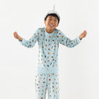 Child wearing light blue space printed pyjamas on a white background.