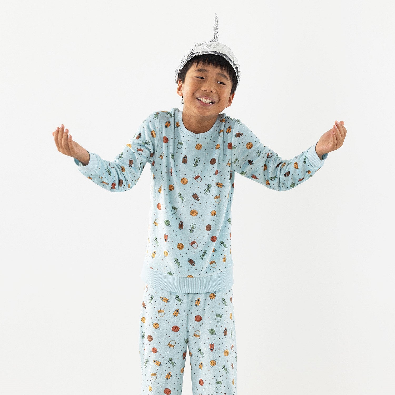 Child wearing light blue space printed pyjamas on a white background.