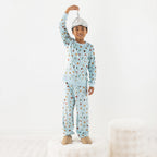 Child wearing light blue space printed pyjamas on a white background.