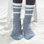 Blue sherpa lined slipper socks with striped cuff detail, worn on a soft white rug.
