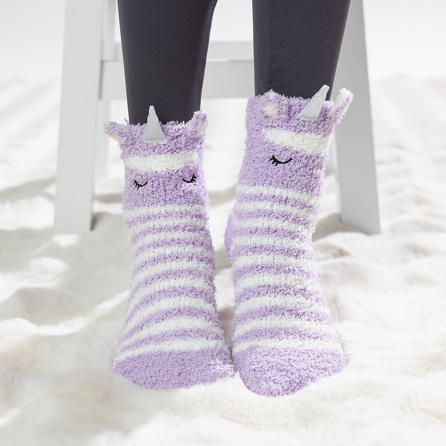 Purple striped kids slipper socks with sherpa lining and cute animal face design, worn on a soft white rug.