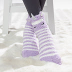 Purple striped kids slipper socks with sherpa lining and cute animal face design, worn on a soft white rug.