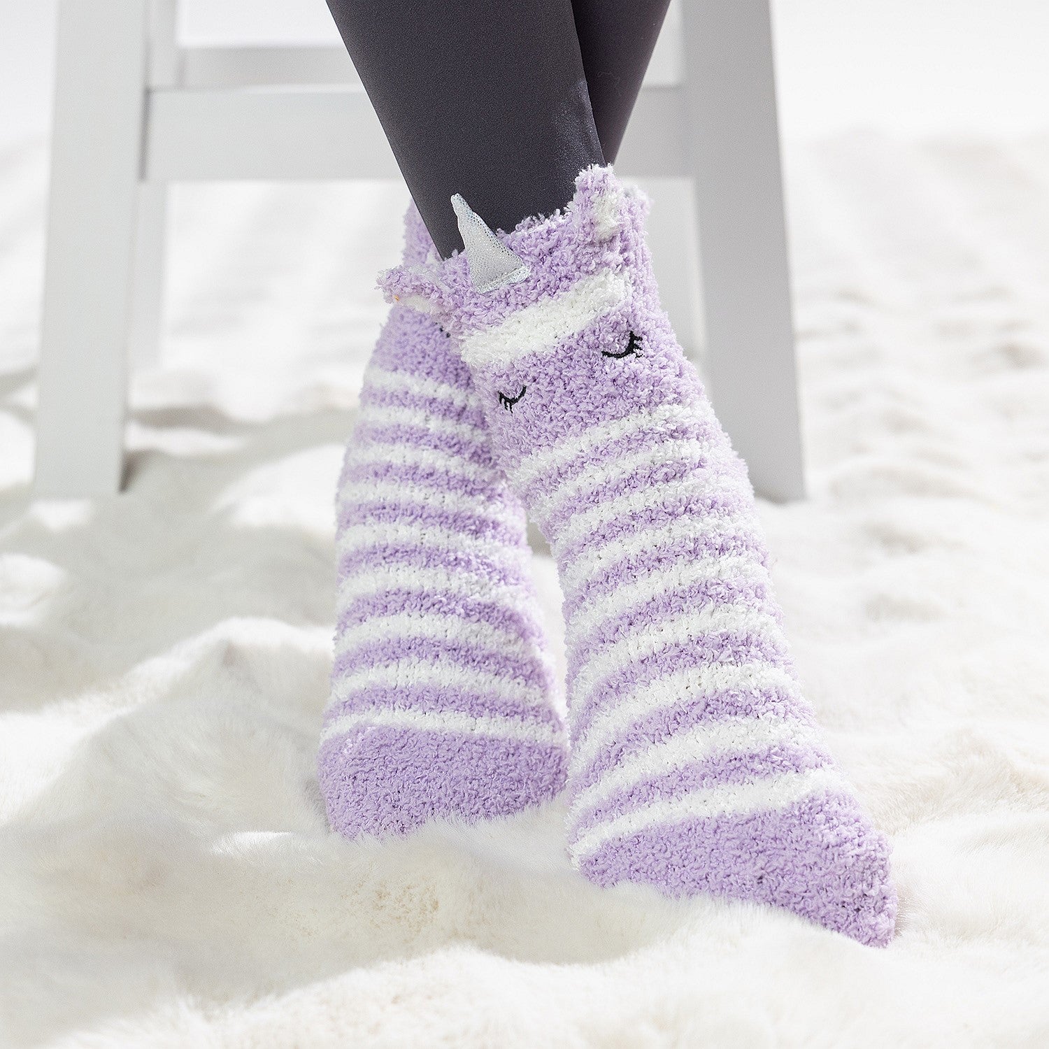 Purple striped kids slipper socks with sherpa lining and cute animal face design, worn on a soft white rug.
