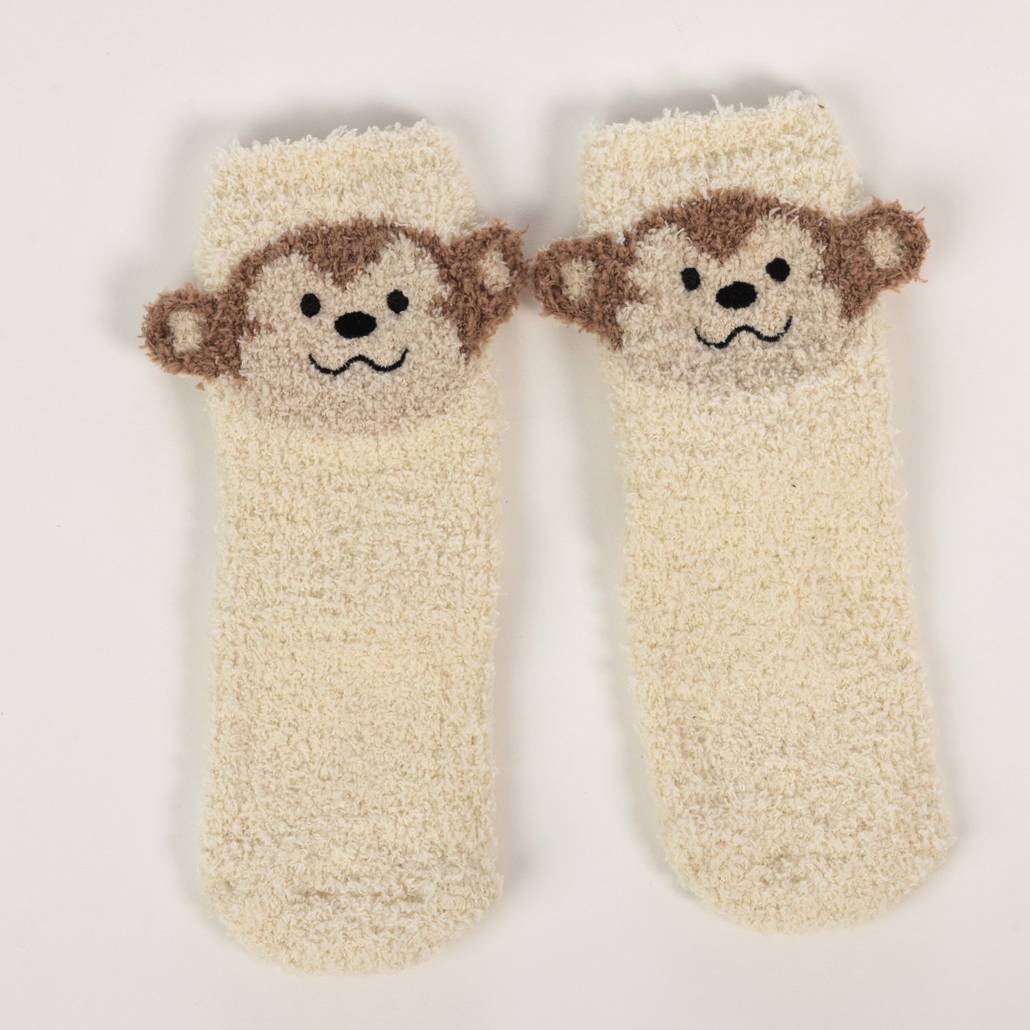 Cream kids bed socks with cute monkey face design,on a white background.