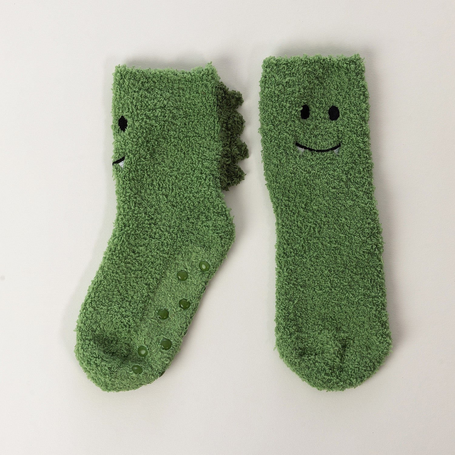 Green kids bed socks with smiling frog face design, on a white background 