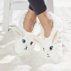 White bunny slipper socks with fleece lining worn on a soft white rug.