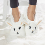 White bunny slipper socks with fleece lining worn on a soft white rug.