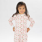 Child wearing pink and red heart print pyjamas posing on a white background.