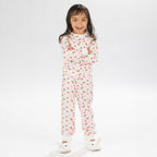 Child wearing pink and red heart print pyjamas posing on a white background.