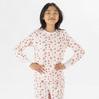 Child wearing pink and red heart print pyjamas posing on a white background.
