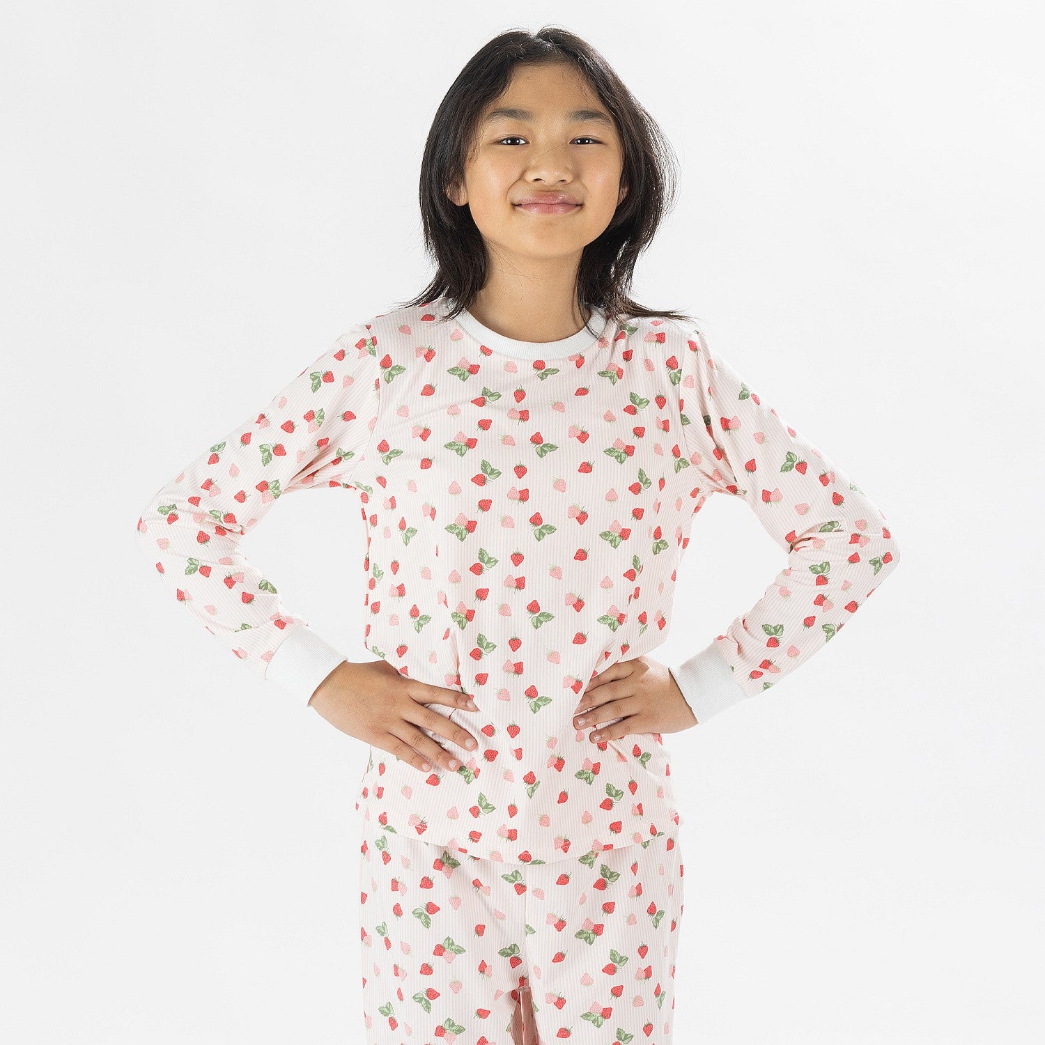 Child wearing pink and red heart print pyjamas posing on a white background.