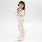 Child wearing pink and red heart print pyjamas posing on a white background.