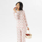 Child wearing pink and red heart print pyjamas posing on a white background.