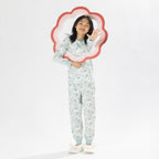 Child wearing a light green printed pyjama set with unicorns on a white background. Wearing bunny slippers.