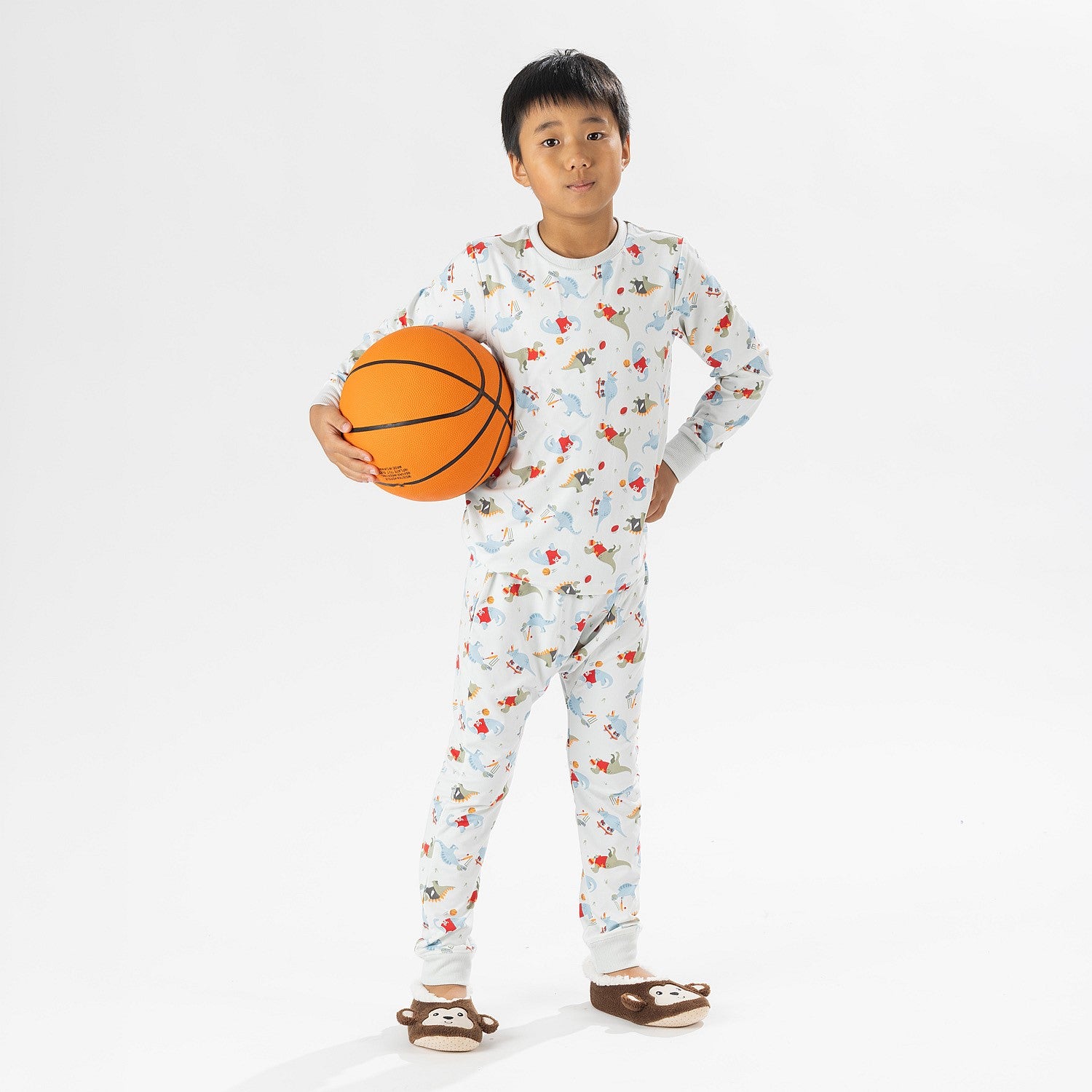 bb&b Sleep Kids Dino Sport knit pyjama twosie worn by a child holding a basketball.