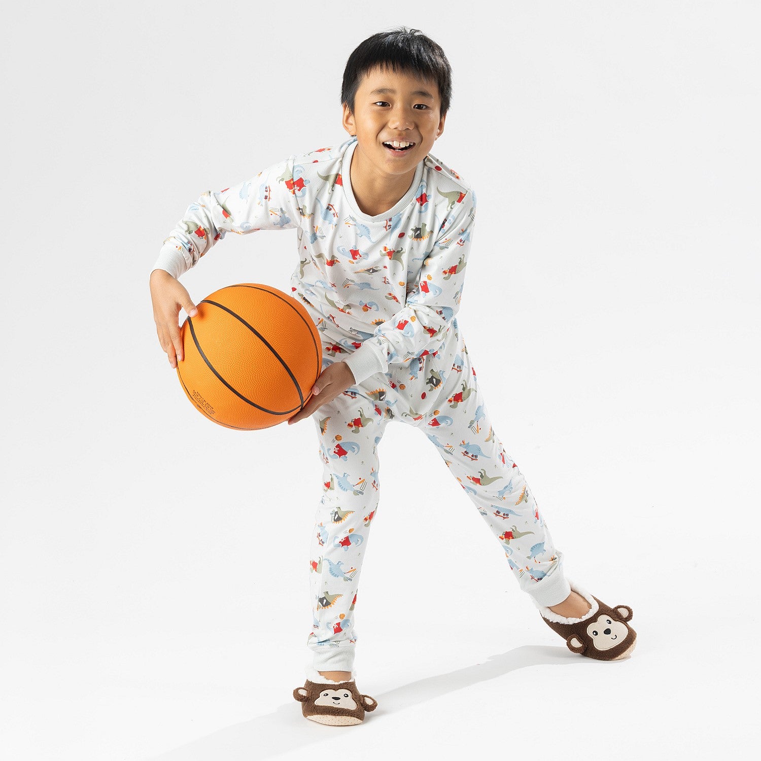 bb&b Sleep Kids Dino Sport knit pyjama twosie worn by a child holding a basketball.