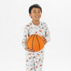 close up bb&b Sleep Kids Dino Sport knit pyjama twosie worn by a child holding a basketball.