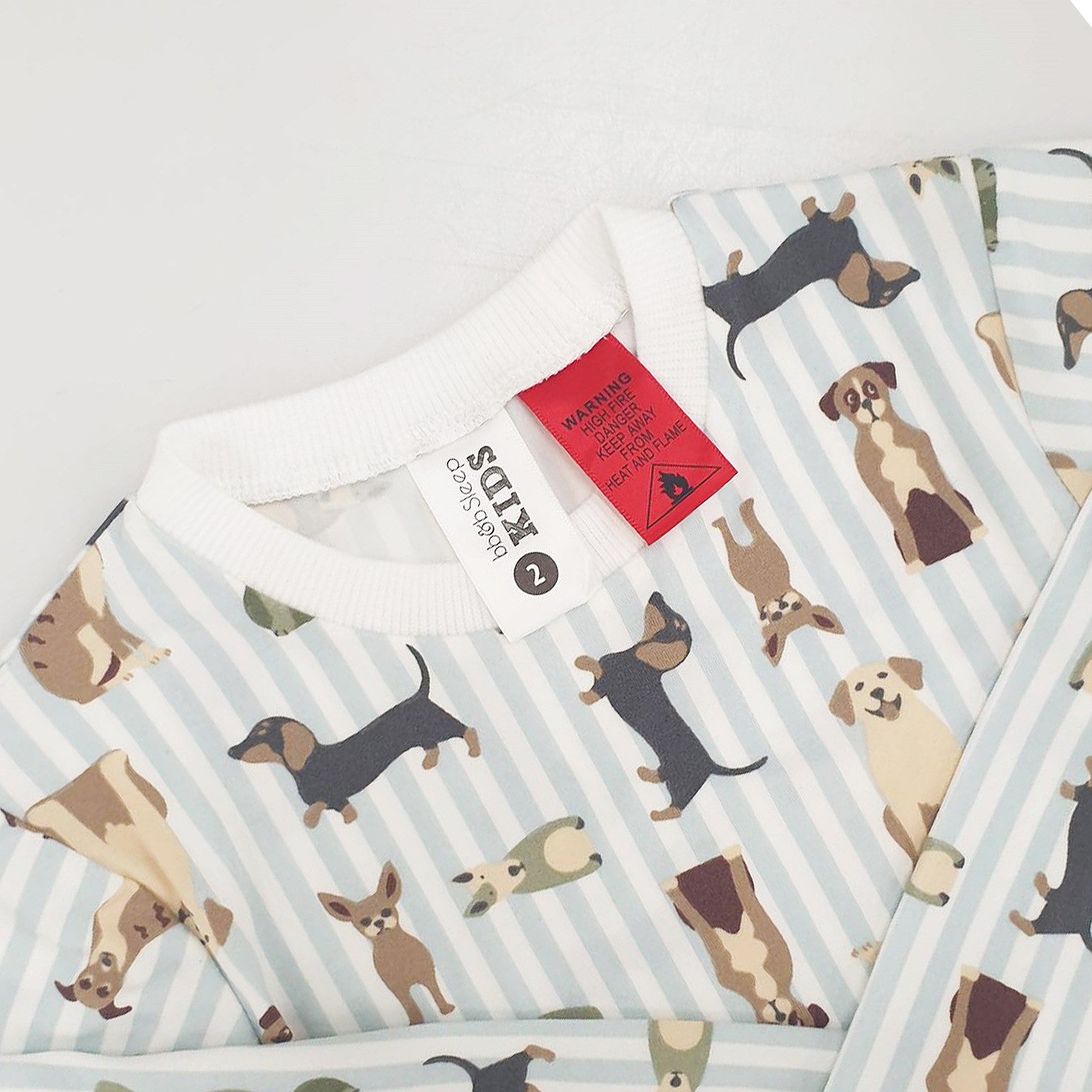 Child wearing bb&b Sleep Kids Dog Stripe knit pyjama twosie up close showing the tags.