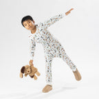 Child wearing bb&b Sleep Kids Dog Stripe knit pyjama twosie while holding a plush dog toy.