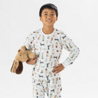 Child wearing bb&b Sleep Kids Dog Stripe knit pyjama twosie while holding a plush dog toy.