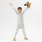 Child wearing bb&b Sleep Kids Dog Stripe knit pyjama twosie while holding a plush dog toy.