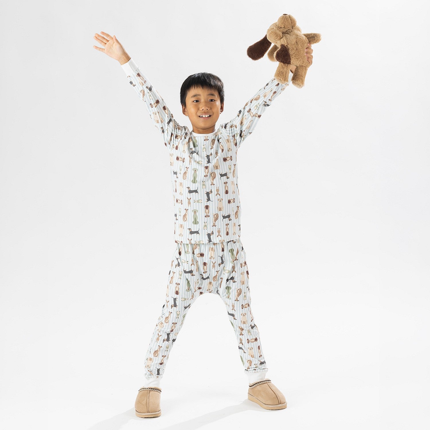 Child wearing bb&b Sleep Kids Dog Stripe knit pyjama twosie while holding a plush dog toy.