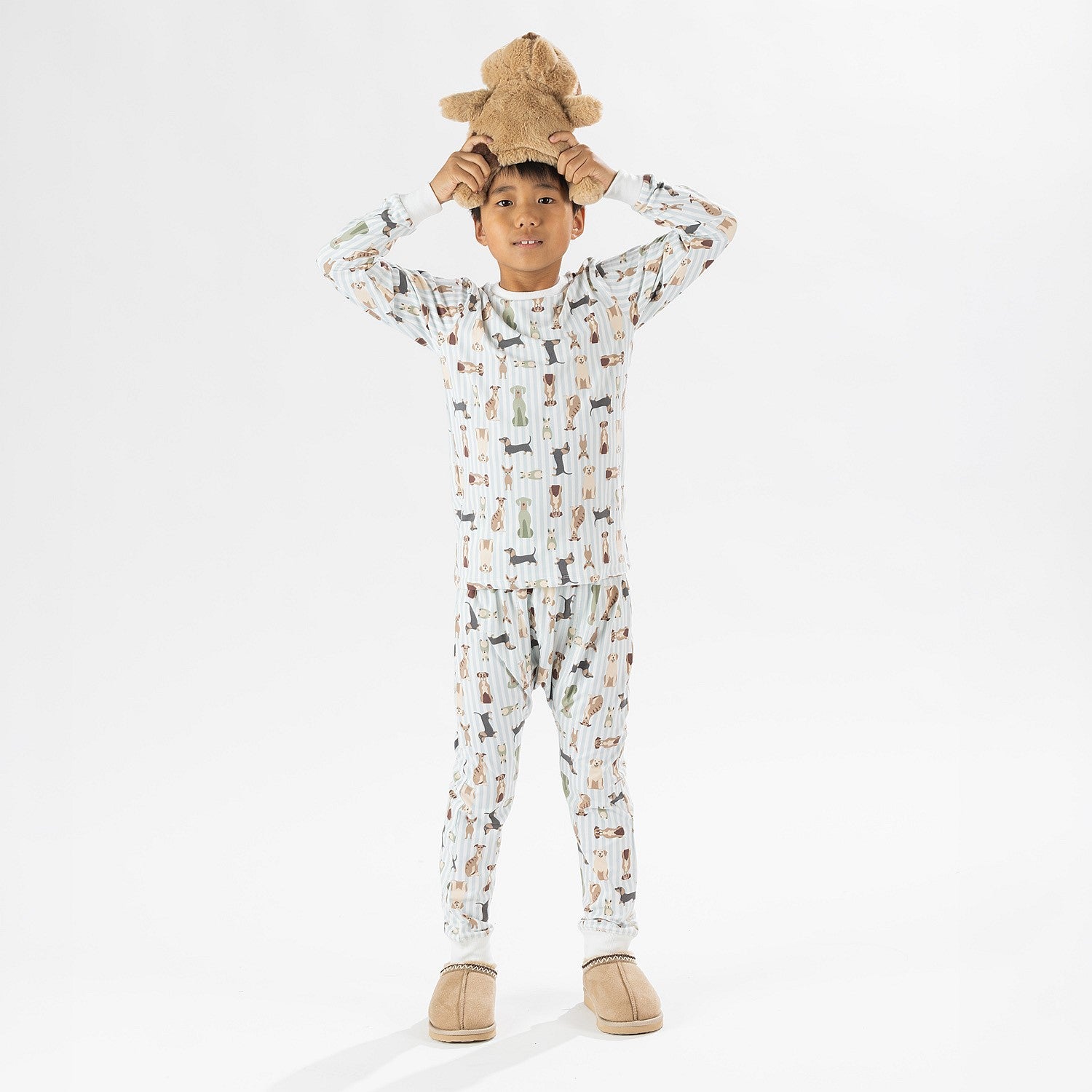 Child wearing bb&b Sleep Kids Dog Stripe knit pyjama twosie while holding a plush dog toy.