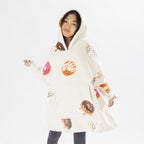 Child wearing a white oversized hoodie with colourful donut playful print on a white background.