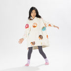 Child wearing a white oversized hoodie with colourful donut playful print on a white background.