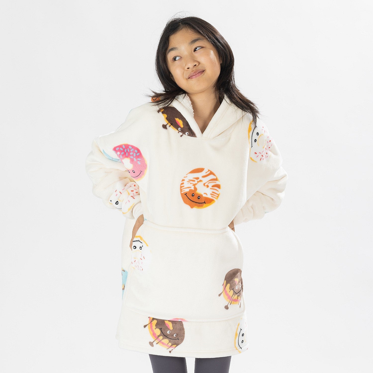 Child wearing a white oversized hoodie with colourful donut playful print on a white background.