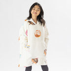 Child wearing a white oversized hoodie with colourful donut playful print on a white background.