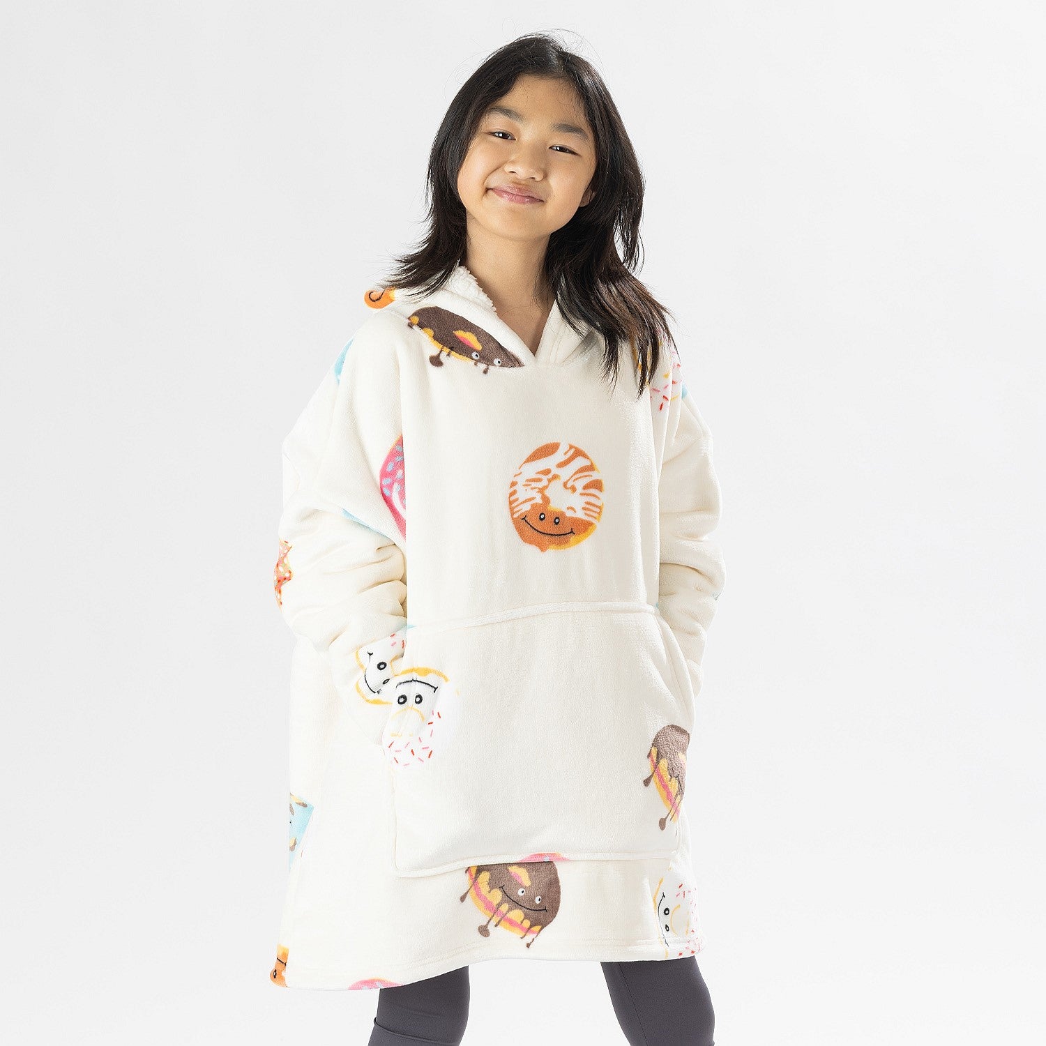 Child wearing a white oversized hoodie with colourful donut playful print on a white background.