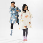 Two children wearing oversized printed hoodies, one in cream and one in blue, standing on a white background.