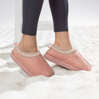 Pink faux fur slippers with soft lining worn on a white rug.