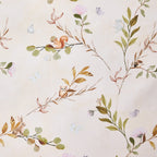 Baby cot styled with natural colour fabric with a delicate leafy vine print in soft green and brown tones. 