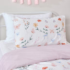 Butterfly print pillowcase and cot cover styled with a soft pink foldover on a white bed.