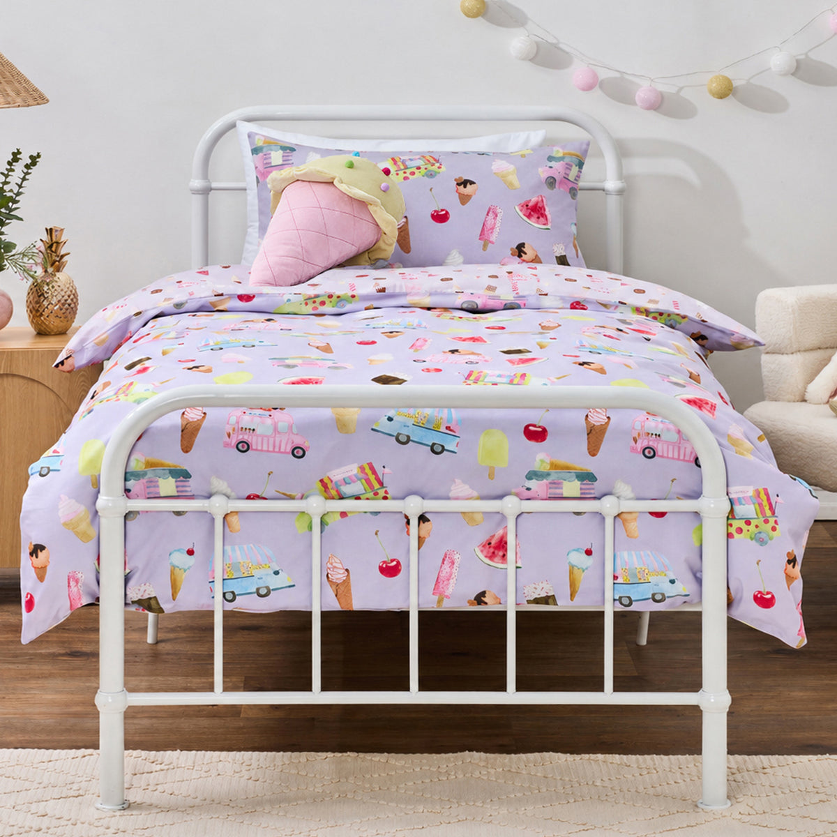 bb&b Kids Ice Cream Shop duvet cover set styled on a white metal bed, featuring a lilac print with colourful ice creams, popsicles, cherries and ice cream trucks.