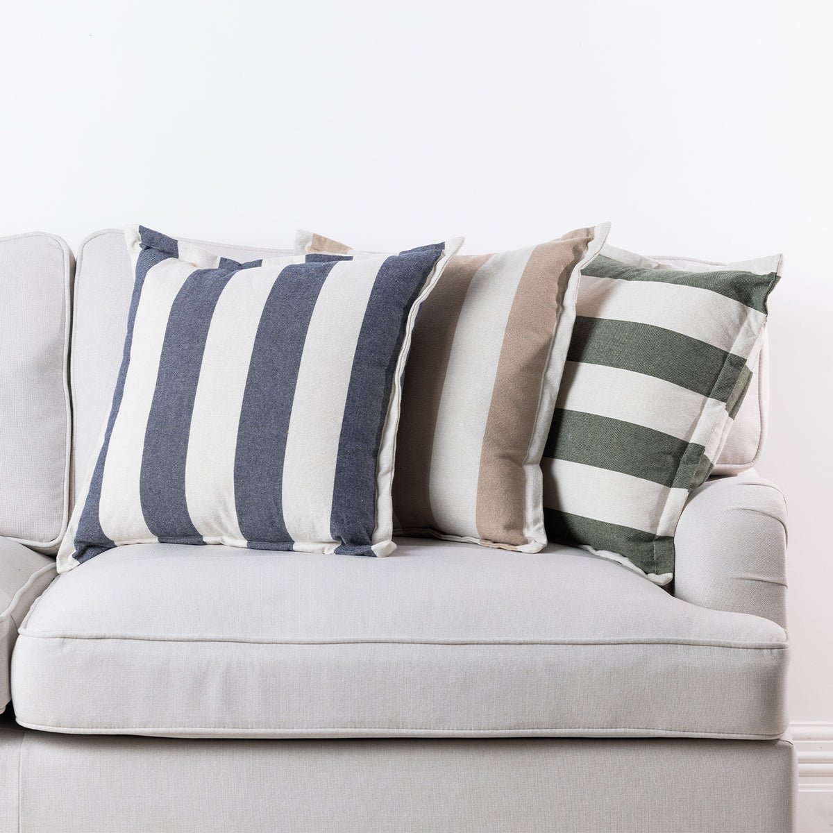 Home Co. Ashley Cushions in Navy, Natural and Olive styled together on a neutral sofa.