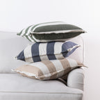 Home Co. Ashley Cushions in Olive, Navy and Natural stacked together on a neutral sofa.