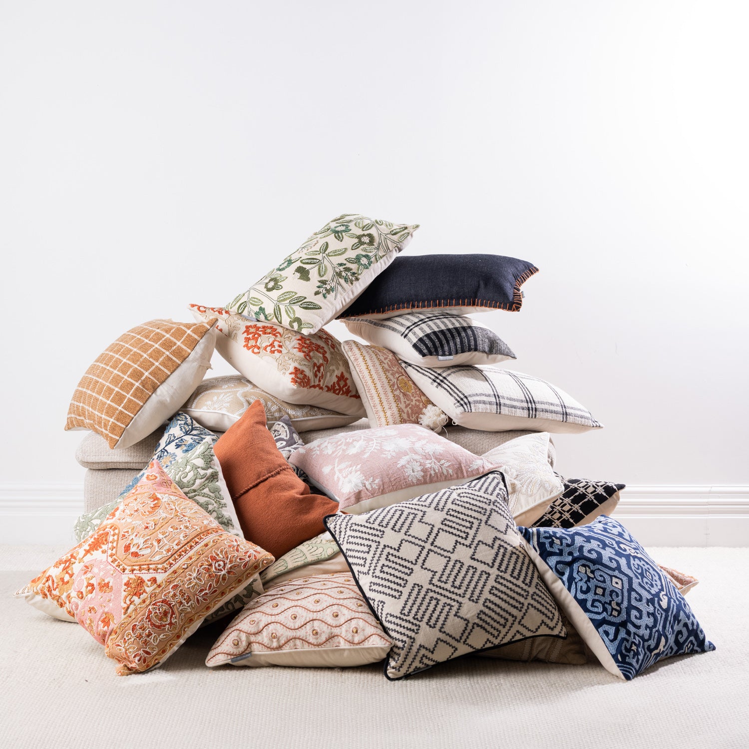 A curated collection of decorative cushions in a mix of embroidered, woven, and printed designs showcases a variety of colours, textures, and patterns to suit any interior style.