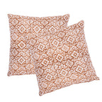 Two square decorative throw pillows with a white floral and geometric block-print pattern on a warm terracotta brown background, shown against a plain white studio background.
