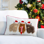 Highland cows Christmas cushion displayed on a white sofa beside a Christmas tree with festive ornaments and warm fairy lights.