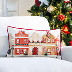 Christmas Wishes Christmas Town Cushion featuring festive townhouses, displayed on a white sofa beside a decorated Christmas tree.