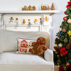 Christmas Town Cushion displayed alongside a gingerbread man cushion on a white sofa beside a decorated Christmas tree.