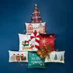 A collection of festive Christmas cushions arranged in the shape of a Christmas tree against a blue background with warm fairy lights.