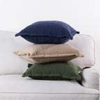 Home Co. Bailey Cushions in Navy, Natural and Olive stacked together on a neutral sofa.
