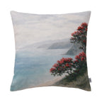 Fieldcrest Coastal Pohutukawa Cushion featuring a misty coastal landscape with calm blue water and vibrant red pōhutukawa blooms on a soft neutral background.
