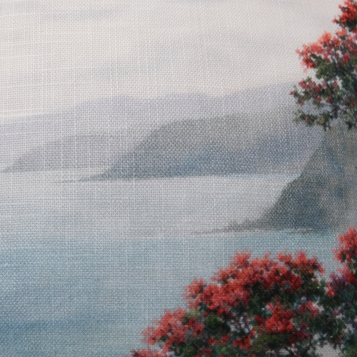 Close-up of the Fieldcrest Coastal Pohutukawa Cushion showing the woven fabric texture, soft coastal scenery and red pōhutukawa flowers.
