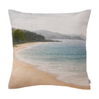 Fieldcrest Serene Coast Cushion featuring a tranquil sandy beach, pale blue water, tree-lined shoreline and misty hills in soft natural tones.