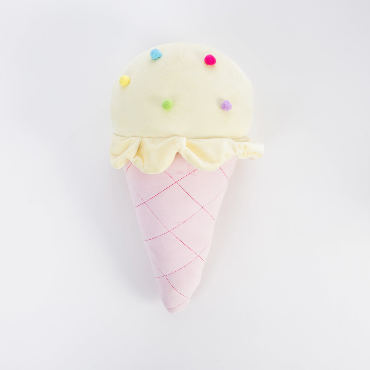 A plush ice cream cone cushion with a pale yellow scoop topped with small colorful pom-pom sprinkles and a pink waffle-cone body, photographed on a clean white background.